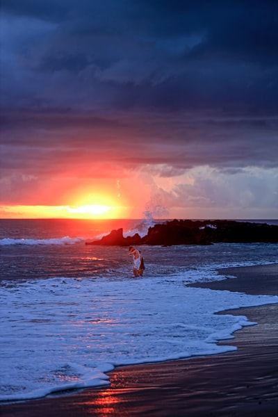 日落时穿着白色衣服在海滩上散步的女人